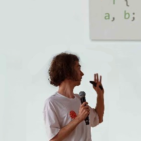 A picture of me giving a talk, looking to the right at some code.